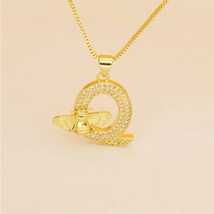 Macro view of gold letter Q pendant with micro-pave zircons and delicate bee detail