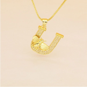 Detailed close-up of gold plated letter U pendant with micro-pave crystals and small bee