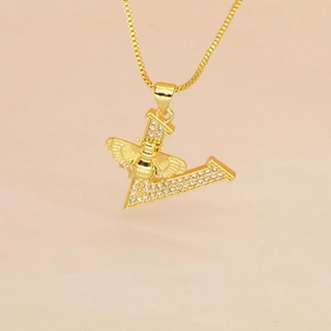 Close-up of gold pendant featuring a crystal-set letter V with a detailed bee charm