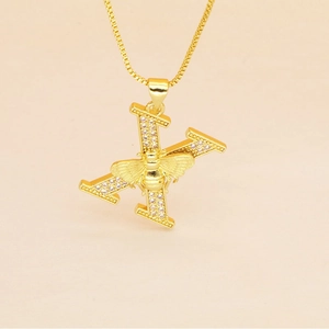 Detail of gold letter X pendant with pavé stones and a small bee on a box chain