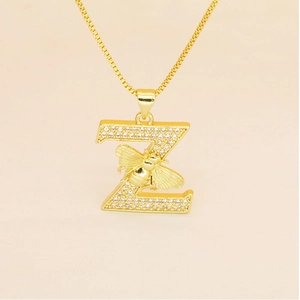 Macro detail of gold letter Z pendant necklace with pave zircons and a small honey bee