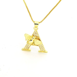Macro view of gold letter A pendant with cubic zirconia inlay and bee detail