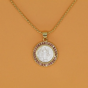 Close-up of Saint Benedict medallion necklace with pink stones and gold plating