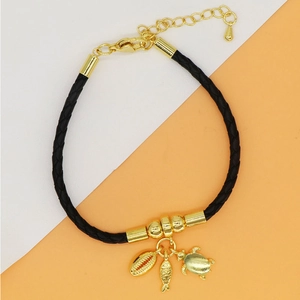 Detail of black cord bracelet featuring gold sea shell, fish, and turtle charms