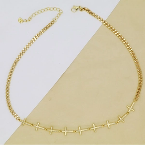 Detailed macro of gold Cuban link chain necklace with nine crystal-encrusted mini crosses