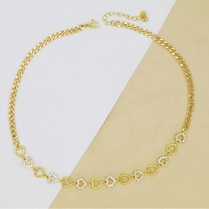 Detail of gold Cuban chain necklace featuring open metal hearts and white zircon stones