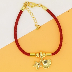 Macro view of red woven leather bracelet featuring golden starfish and seashell charms