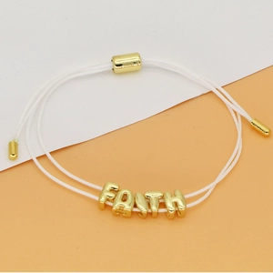 Detail van de verstelbare geweven armband met gouden Faith kralen en metalen schuifsluiting