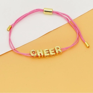 Detailweergave van de roze gevlochten armband met gouden letterkralen en het woord CHEER