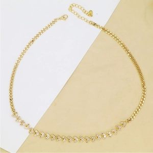 Detail of gold Cuban link necklace featuring micro-pave heart pendants and a lobster clasp