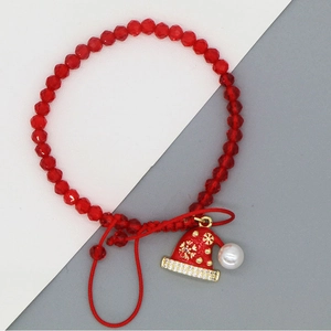 Detail eines roten Perlenarmbands mit Emaille-Weihnachtsmütze und goldenen Schneeflocken