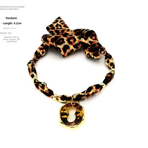 Detail of bohemian leopard print fabric necklace with amber resin pendant in gold frame