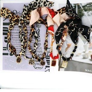 Dettaglio ravvicinato di collane in foulard di seta leopardata con inserti dorati