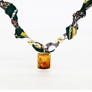 Detail of silk scarf necklace with amber resin pendant and golden beaded design
