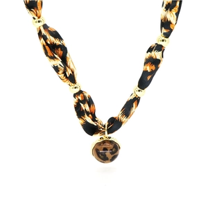 Primo piano della collana in tessuto leopardato con perle dorate e ciondolo a cuore