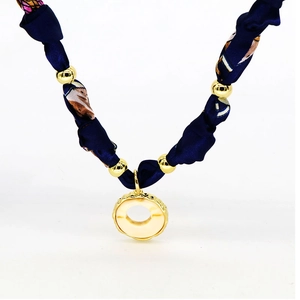 Detail of navy blue silk scarf necklace with gold metal beads and round heart pendant