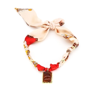 Dettaglio della collana a foulard in tessuto con perle dorate e ciondolo in ambra