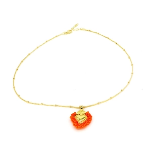 Makroaufnahme der goldenen Sacred Heart Kette mit handgefertigten orangefarbenen Perlen
