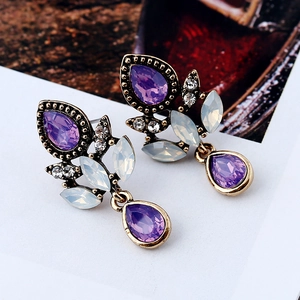 Gros plan de boucles d'oreilles dorées vintage avec cristaux violets et opales