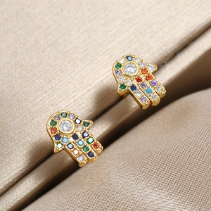Hamsa Hand Ohrringe mit Goldbeschichtung und bunten Zirkoniasteinen auf Satin-Hintergrund