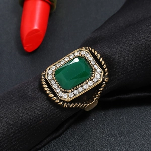Vintage gold ring with emerald green stone and sparkling crystal halo on black silk