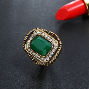 Macro shot of vintage gold ring with green gemstone and crystal halo on black leather
