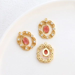 Dettaglio macro di ciondoli ovali placcati oro 14k con gemme rosa e alone di zirconi