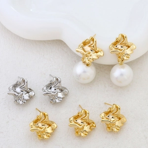 Irregular textured gold and silver earrings with pearl accents on a white decorative tray