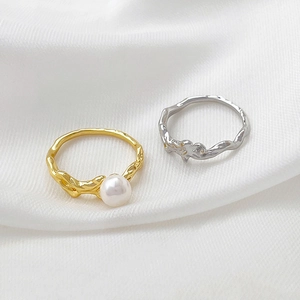 Detail of gold tree vine ring with pearl and silver lava textured ring on white silk fabric