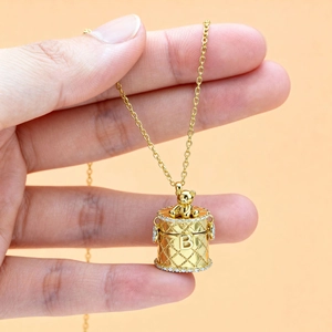 Golden quilted cylinder pendant necklace with a sitting bear and zircon accents
