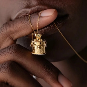 Macro shot of golden waffle-textured cylinder pendant with bear charm and zircon details