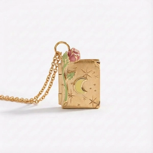 Detailed macro view of vintage golden book locket with enamel rose and moon carving