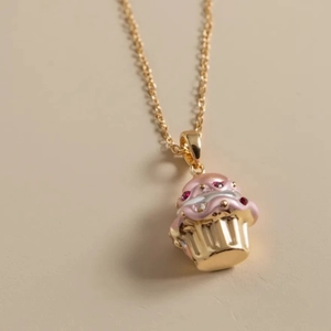 Dettaglio del ciondolo a forma di cupcake rosa con cristalli e collana dorata
