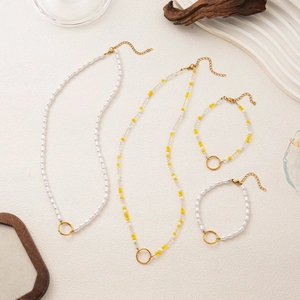 Ensemble de colliers et bracelets en perles faits main avec breloques dorées sur fond texturé