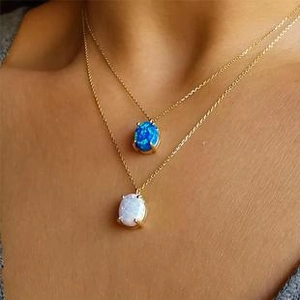 Close-up of double-layer gold necklace with blue and white opal pendants on a model