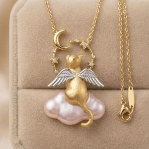 Makroaufnahme von Engel-Katzen-Anhänger mit rosa Perle und goldenem Mond-Stern-Ring