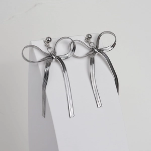 Dettaglio di orecchini a catena serpente d'argento con design a fiocco su supporto bianco