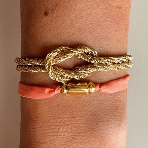 Pulsera vintage de nudo dorado con banda de tela rosa y un cierre de metal elegante