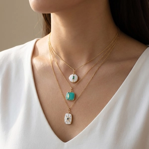 Detailed close-up of triple-layered gold necklaces with enamel and turquoise pendants