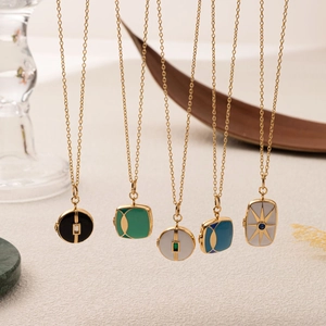 Close-up of gold lockets with colorful enamel and gemstone details hanging in a group