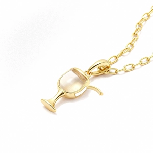 Macro shot of gold-plated wine cup pendant with milky stone on white silk fabric