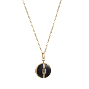 Detail of vintage gold necklace featuring a round black enamel pendant with zircon stone