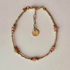 Beaded gold chain bracelet featuring faceted pink quartz stones and a round charm tag