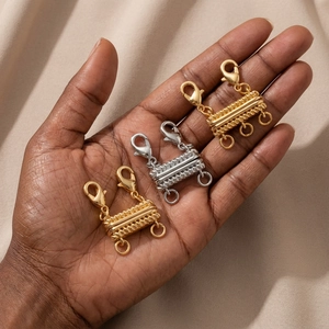 Golden and silver multi-layer magnetic necklace clasps held in hand for jewelry stacking