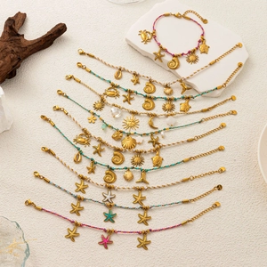 Detailansicht gewebter Meeres-Armbänder mit goldenen Seestern- und Muschel-Anhängern