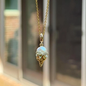 Makroaufnahme Eiskrem-Anhänger mit Barockperle, Diamantschleife und Goldtüte