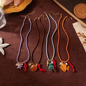 Flat lay of ocean-themed starfish and shell pendants on colorful woven rope necklaces