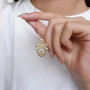 Gros plan d'un collier doré avec cœur, nœud et breloques lune et étoile portées