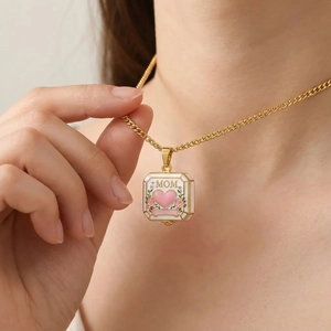 Macro view of square MOM pendant with gold chain, pink heart and floral details
