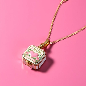 Detail of square 18k gold plated mom locket with floral enamel pattern on pink background